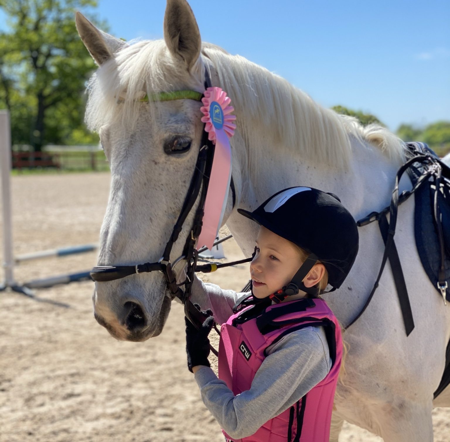 Barn som står vid ponnyn Madam. En rosa prisrosett på tränset.