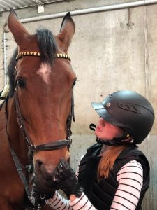 En tonårsflicka håller en häst i stallet